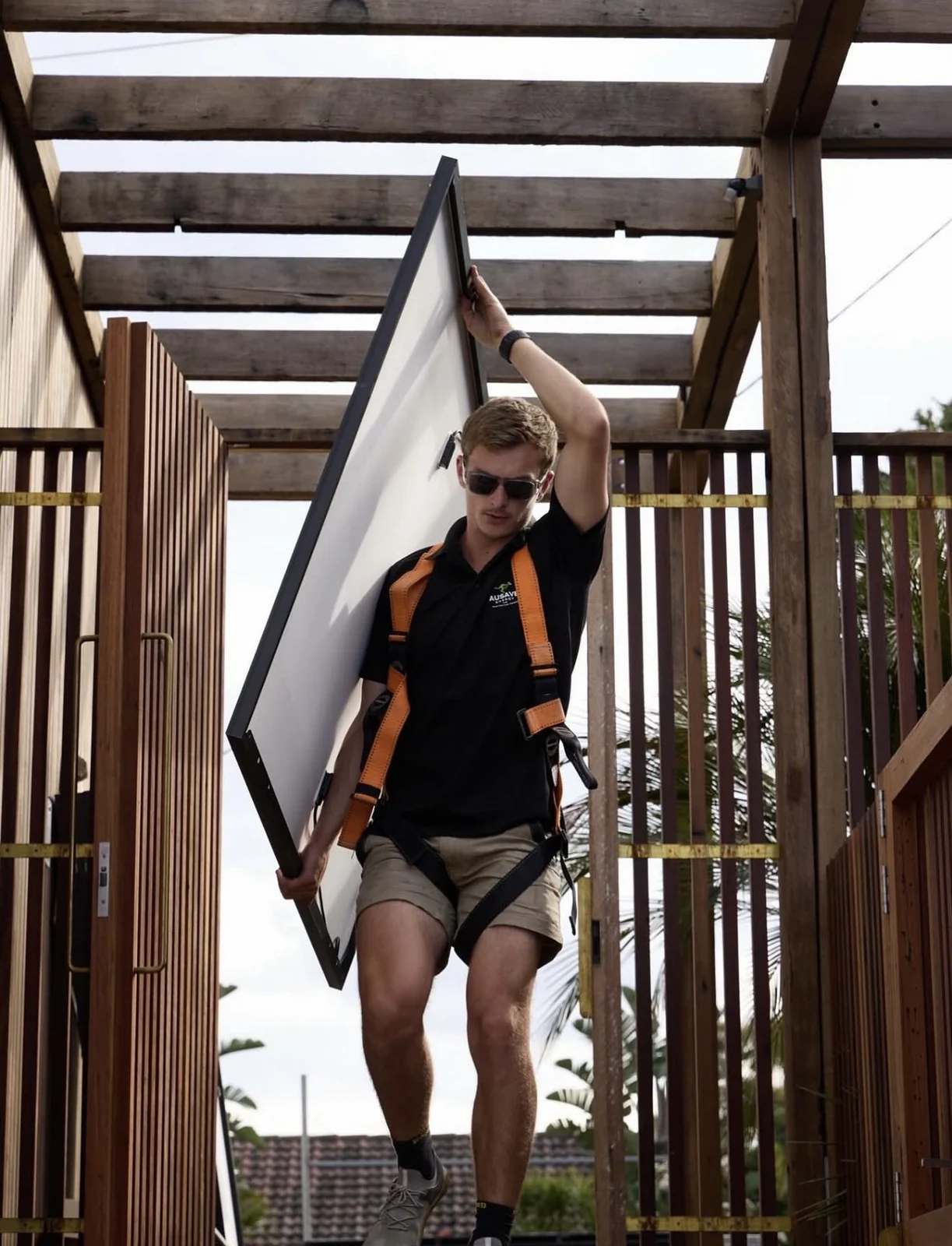 Ausave installer carrying a solar panel on site