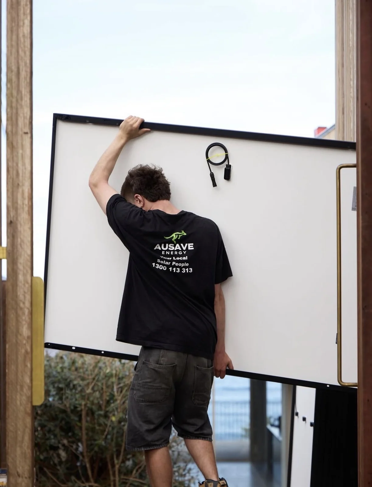 Ausave installer lifting a solar panel into place